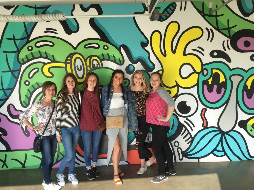 Students standing in front of a colorful mural.